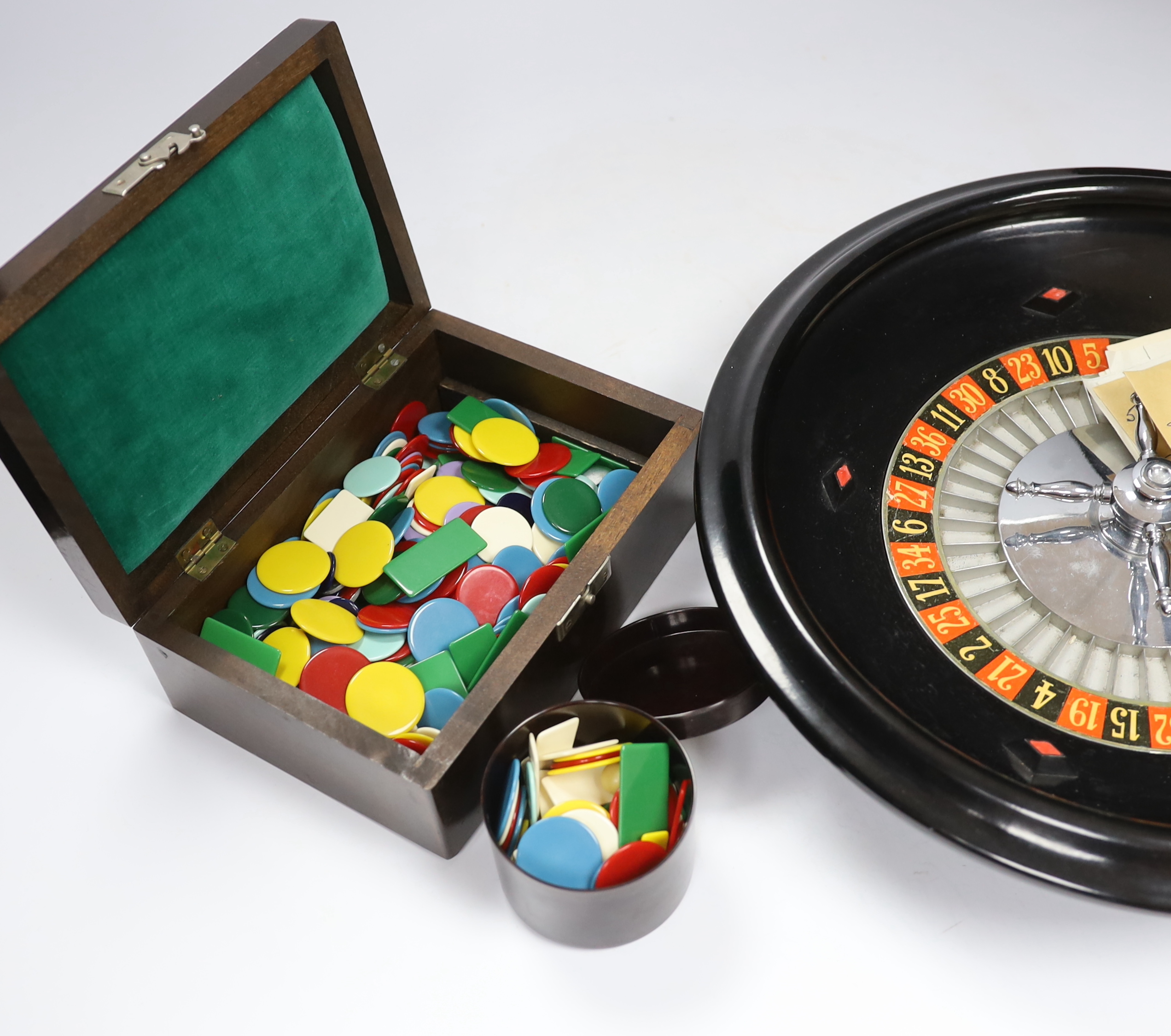 A vintage roulette wheel with gaming counters etc.